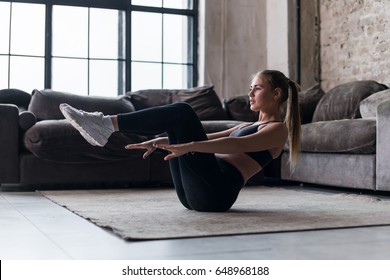 Slim sporty girl doing v-ups abs workout at home