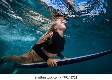 Slim surfer blonde model in bikini with surf board dive underwater with joy under ocean surface. Family lifestyle, people sea water sport lessons and beach swimming activity on summer vacation