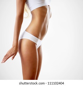 Slim tanned woman's body. Isolated over gray background.