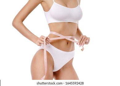 Slim tanned woman's body over gray background - waist measurement