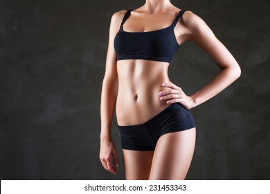 Slim tanned woman's body  over dark grey background