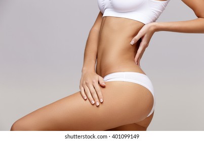 Slim tanned woman's body over gray background