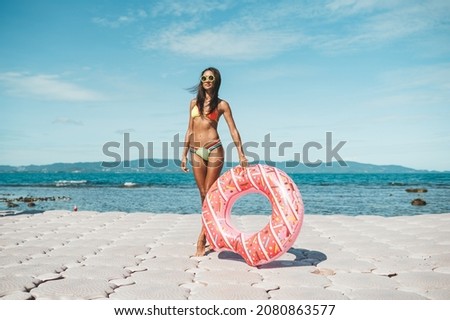 Slim woman in bikini with inflatable ring at the beach