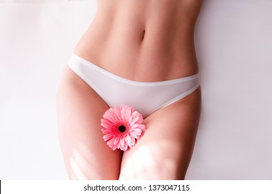 slim woman dressed in white panties, holding a pink flower . Gynecology, menstruation, the concept of woman genital health.