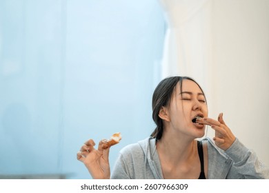 Mujer delgada que termina el croissant malo del chocolate. Mujer sana hermosa perdió el control a los dulces poco saludables que deciden no hacer ejercicio del equilibrio. Mujer hermosa asiática gana peso comiendo el croissant del chocolate.