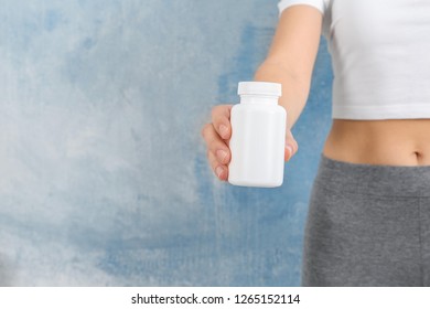 Slim Woman Holding Bottle Of Weight Loss Pills Against Color Background, Closeup. Space For Text