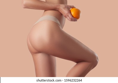 Slim Woman Is Holding Orange. Perfect Female Buttocks Without Cellulite. Beautiful Woman's Butt In Underwear. Body Care And Anti Cellulite Massage