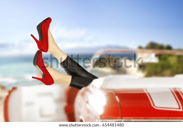 Slim woman\
legs and red car with summer trip time\
