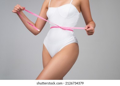 Slim woman with measuring tape around the waist line. Fit fitness girl measuring waistline with measure tape. Slim woman measuring waist after diet. Slim body, perfect waist.