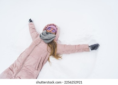 Slim woman with pink winter coat on making a snow angel. High quality photo - Shutterstock ID 2256252921