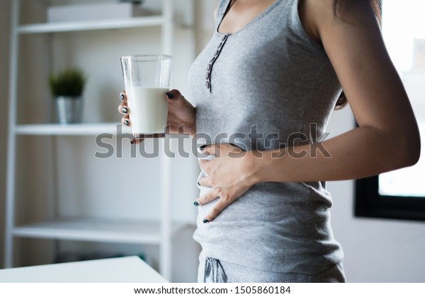 コップ1杯の牛乳を持つ腹痛と痛みを持つスリムな女性 乳製品不耐性 乳糖不耐性 アレルギー 医療コンセプト の写真素材 今すぐ編集
