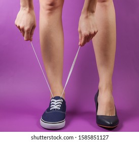 Slim Woman's Legs In Two Different Shoes With Heels And Sneakers On Purple Background. Creative Fashion Shot