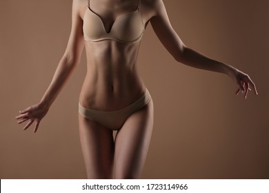 Slim young woman dancing in lingerie on a beige background. Fitness, diet, skin and body care