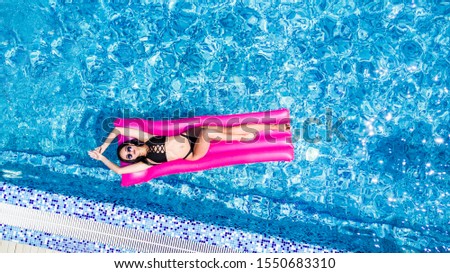 Slim young woman lying on air mattress in the pool