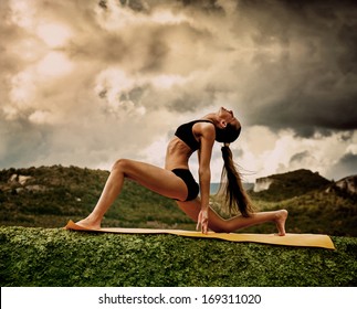 Slim Young Woman Makes Warrior Yoga Pose 