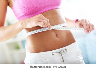 Slim Young Woman Measuring Her Waist With A Tape Measure