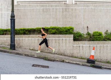 Slim Young Woman Running Uphill On Sidewalk Of City Street. Female Athlete Training Outside