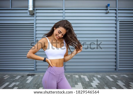 Slim young woman in sport outfit, happy, joyful, jumping. Happy young woman in sports clothing smiling.  Muscular fitness model on black background looking away at copy space.