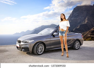 Slim young woman and summer car on road in Gran Canaria island 