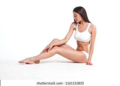 Schlanke junge Frau in Unterwäsche auf weißem Hintergrund. Konzept der Haut- und Körperpflege