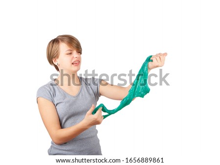 The slime is disgusting: young girl grimacing while she squeezing a  green slime looks like gunk. Studio shot isolated on white background.