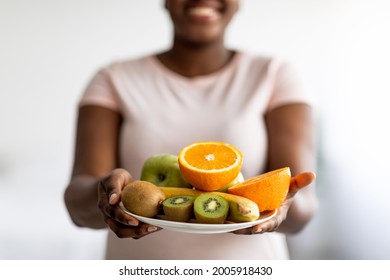 Slimming Diet, Weight Loss And Healthy Lifestyle Concept. Cropped View Of Plus Size Black Woman Holding Plate Of Fresh Fruits Indoors, Selective Focus. Unrecognizable Young Lady Eating Nutritious Meal