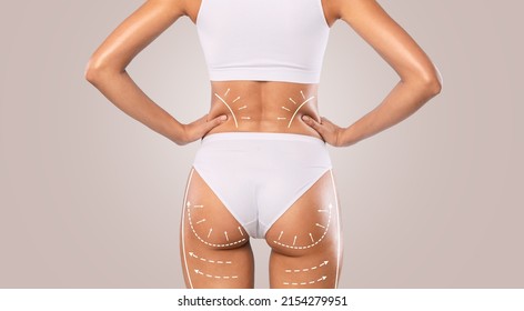 Slimming And Tightening Concept. Closeup cropped rear view of young female model in white panties posing with outline massage lines and arrows on her back and buttocks, isolated on studio background