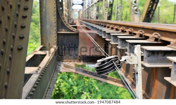 Sling cable\
for changing train tracks. A wire rope with a pulley for\
controlling the rail switch is mounted on the side of the rail on a\
steel bridge with copy area. Selective\
focus
