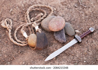 Sling of David with Five Smooth Stones and Goliaths Sword in the Dirt
