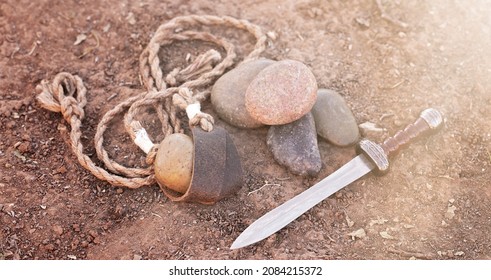 Sling Of David With Five Smooth Stones And Goliaths Sword In The Dirt