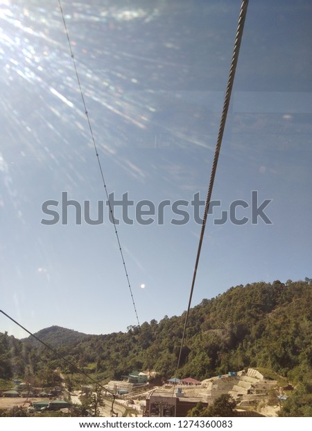 The sling wire of cable car between\
Rathittaung station and Kyaikhtiyo Pagoda on the skyline with blue\
sky  and mountains,view from inside the cable car.\
