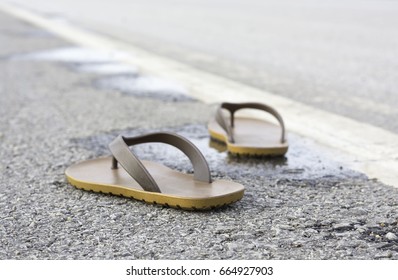 Slipper 2 side placed on the concrete road with water on the surface of the road.