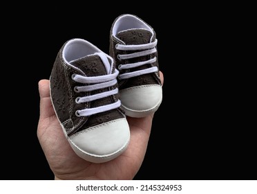 Slippers for babies in hand. Footwear for the smallest children. Children's shoes of small size, isolated on black.