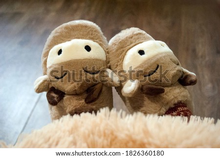 Slippers on female legs. Soft comfortable slippers. Cozy house slippers in the shape of a bull / cow, New Year's house clothes. Year of the bull.