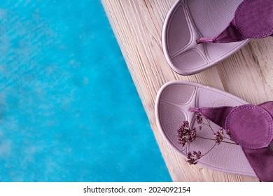 Slippers On A Wooden Plinth Near Blue Water