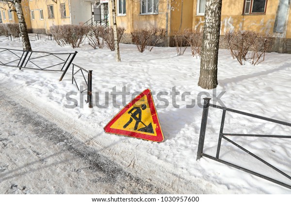 slippery road and a broken fence in the background of\
the warning 