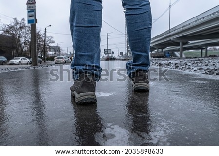 Slippery road covered ice. Man's foots on frozen winter way after freezing rain