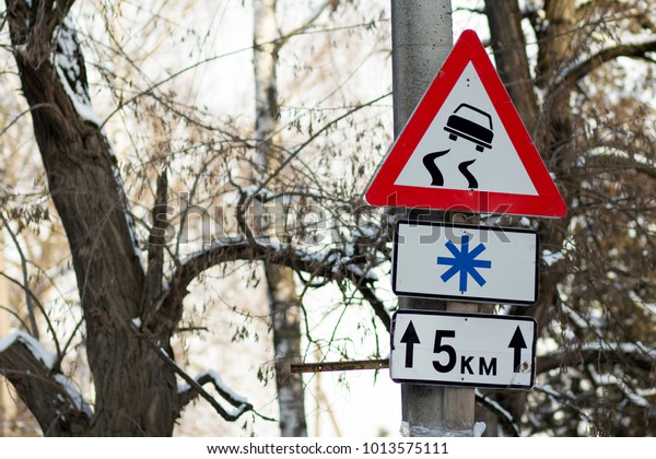 Slippery road warning\
sign on concrete pole.