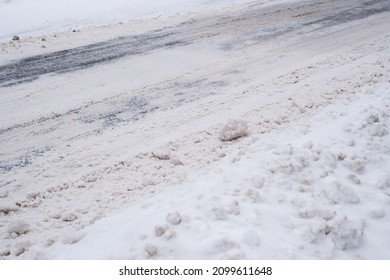 Slippery Snowy City Road  During Winter. Difficult Weather Conditions. Street And Sidewalk Under Snow Piles. Dangerous Traffic.