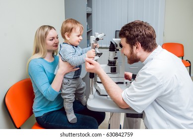 Slit Lamp Examination. Biomicroscopy Of The Anterior Eye Segment. Basic Eye Examination. Mother Holds Child During Eye Exam.