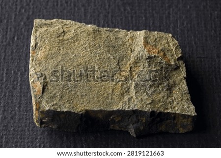 SLIVER OF SLATE  WITH FLAT PLANES BEARING PARTIALLY OBSCURED DULL LUSTER
