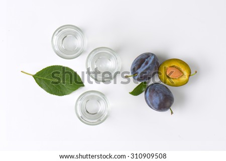 slivovitz (plum brandy) and fresh plums on white background
