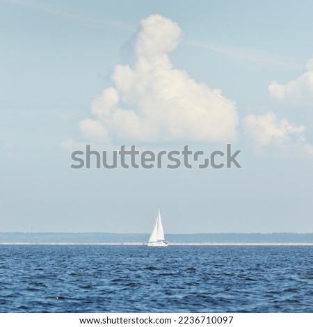 Sloop rigged yacht sailing in the Baltic sea. Dramatic sky after the storm, cumulus clouds. Transportation, travel, cruise, yachts racing, sport, recreation, leisure activity. Panoramic view