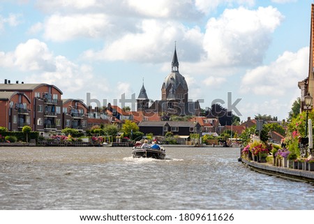 A sloop sails over the old Rijn near the South-Holland village of Leiderdorp the Netherlands. On a cloudy day.
