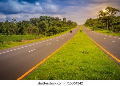 Slope highway with sunshine and green traffic island. Four lane highway with green traffic island. The Provincial immense road passing through a green forest. 
