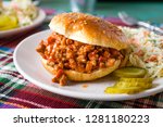 Sloppy Joe sandwich served on a plate with coleslaw salad and pickles