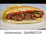   sloppy joe sub top with onions and peppers with a side of chips