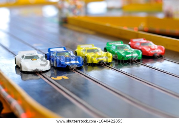 Slot car racing. Five cars with damaged bumpers at\
the start.