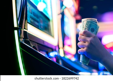 Slot Machine Play Time. Female Gambler Hand hold money bill ready to win the game with one best shot casino close up