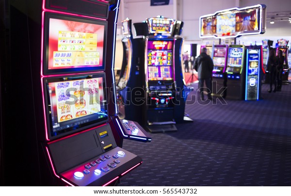 老虎机是在赌场室看到 人们在后台玩其他老虎机 库存照片 立即编辑